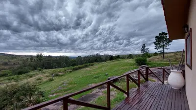 a wooden balcony with a view of a field at Cabaña Tanti Montaña del Vigía in Tanti