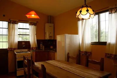 a kitchen with a table and a refrigerator and windows at Cabaña Tanti Montaña del Vigía in Tanti