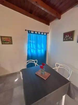 a dining room with a blue curtain and a table and chairs at Bungalow a metros del centro in Villa General Belgrano