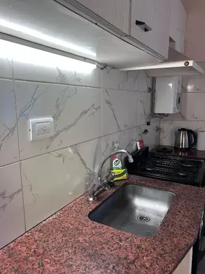 a kitchen counter with a sink and a stove at Bungalow a metros del centro in Villa General Belgrano