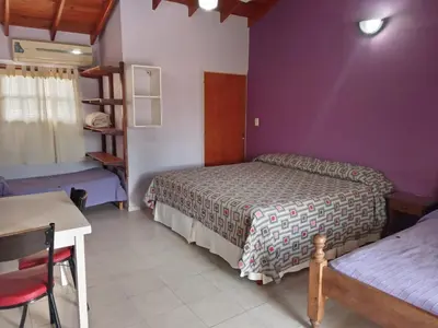 a bedroom with two beds and a table and a desk at Los Estribos Merlo in Merlo