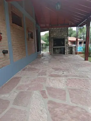 an outdoor patio with a stone floor and a fireplace at Los Estribos Merlo in Merlo