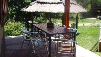 a wooden table with chairs and an umbrella at Los Estribos Merlo in Merlo