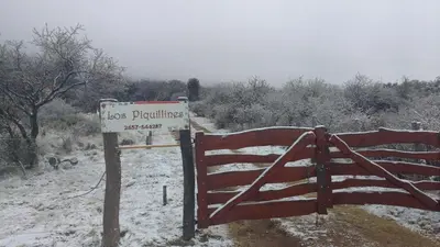 a sign on a gate with a snow covered fence at Cabañas 