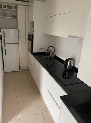 a kitchen with white cabinets and a black counter top at Finlay Departamento in Villa Carlos Paz