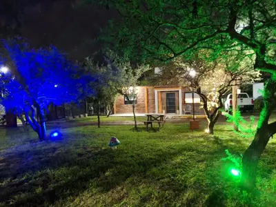 a person sitting in the grass at night with blue lights at Cabañas mauro in Tanti