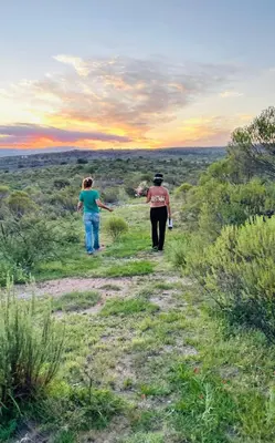 two people walking down a trail in a field at Cabaña Tanti Estancia La Escondida in Tanti