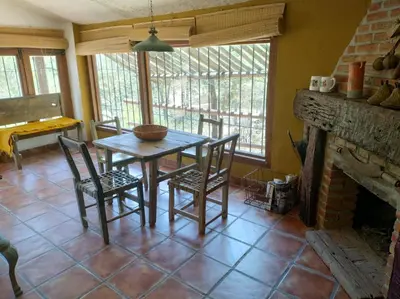 a dining room with a table and chairs and a fireplace at Cabaña Tanti Estancia La Escondida in Tanti