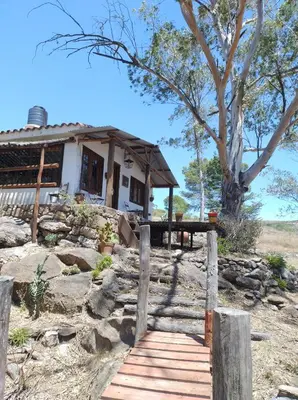 a house with a wooden walkway in front of it at Cabaña Tanti Estancia La Escondida in Tanti