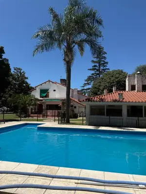 a palm tree in front of a house with a swimming pool at Cabaña kempes Córdoba in Cordoba