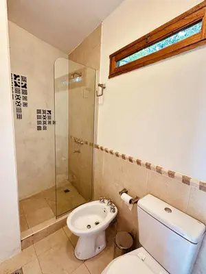 a bathroom with a toilet and a glass shower at La Chascona Suite in Merlo