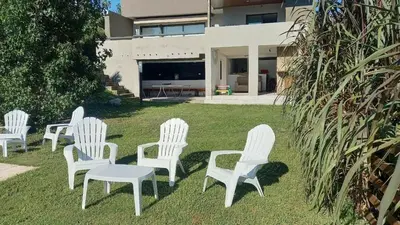 a group of white chairs sitting in the grass at Alojamiento en Villa La Bolsa in La Bolsa