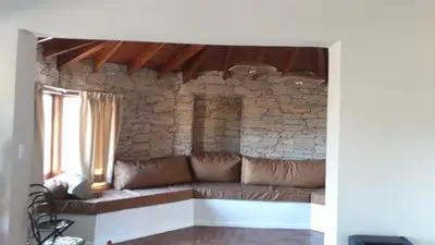 a couch in a living room with a stone wall at Liquidambar in Villa General Belgrano