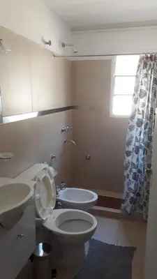 a bathroom with a toilet and a sink and a window at Liquidambar in Villa General Belgrano