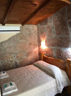 a bedroom with a bed in a stone wall at Cabañas La Cautiva in Tanti