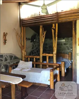 two beds in a room with wooden beams at Cabañas La Cautiva in Tanti
