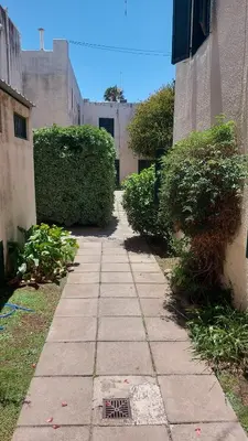 a walkway between two buildings with bushes on each side at Castillo Del Lago Hospedaje Compartido in Villa Carlos Paz