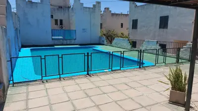 a swimming pool with two chairs and a table at Castillo Del Lago Hospedaje Compartido in Villa Carlos Paz