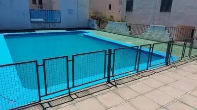a large swimming pool with a fence around it at Castillo Del Lago Hospedaje Compartido in Villa Carlos Paz