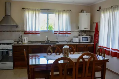 a kitchen with a table and chairs and a kitchen with a stove at Casa Almendro-Chumamaya-Villa de Merlo in Country Club Chumamaya