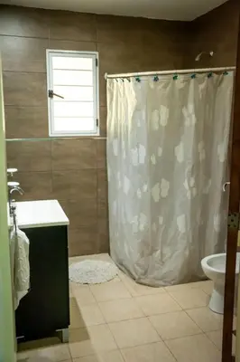 a bathroom with a shower curtain and a toilet at La Tranquilidad in Merlo