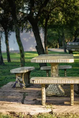 three picnic tables in a park with trees in the background at La Tranquilidad in Merlo