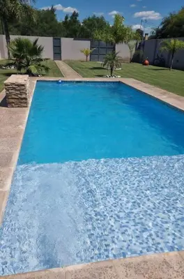 a large blue swimming pool in a yard at Cabaña De La Sierra in Villa Yacanto