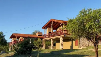 a house with a balcony on the side of it at Cabañas la posada de kika in Arroyo de Los Patos