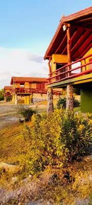 a building with a porch on a field at Cabañas la posada de kika in Arroyo de Los Patos