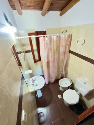 a bathroom with two toilets and a pink shower curtain at Cabañas la posada de kika in Arroyo de Los Patos