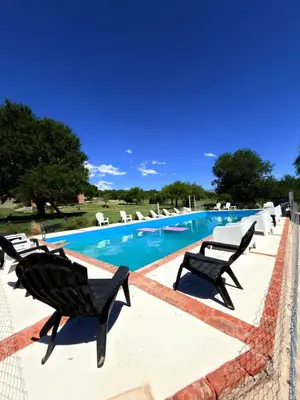 a swimming pool with chaise lounge chairs next to it at Cabañas la posada de kika in Arroyo de Los Patos