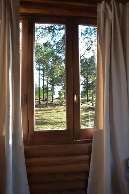 a wooden door with curtains and a window at Alli Allpa Finca y Cabañas de Montaña in Villa Yacanto