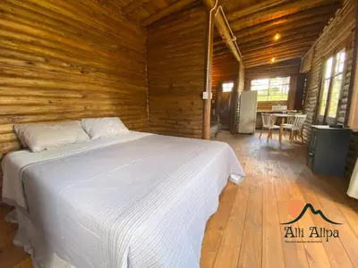 a bedroom with a white bed in a wooden room at Alli Allpa Finca y Cabañas de Montaña in Villa Yacanto