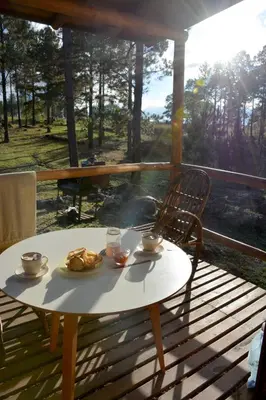 a table with a plate of food on a porch at Alli Allpa Finca y Cabañas de Montaña in Villa Yacanto