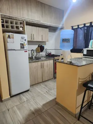 a kitchen with a white refrigerator and wooden cabinets at Posada Abuelo Miguel in Villa Cura Brochero