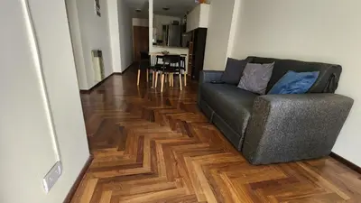 a living room with a couch and a wooden floor at Departamento Salguero Nueva Córdoba in Cordoba