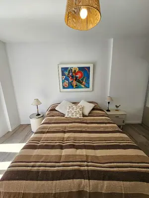 a bedroom with a large bed with a striped blanket at Dpto Ambrosio Olmos 1090 - Pileta, Asadores, Terraza, Quincho in Cordoba
