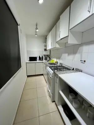 a kitchen with white cabinets and a stove top oven at Departamento Duarte Quirós in Cordoba