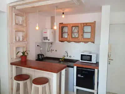 a kitchen with a counter with stools and a microwave at Monoambiente blvd San juan in Cordoba