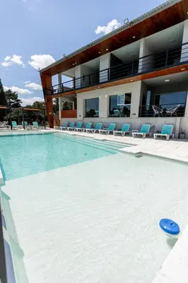 a large swimming pool with chairs and a building at BUENA VIDA I Apart Hotel in Villa Icho Cruz