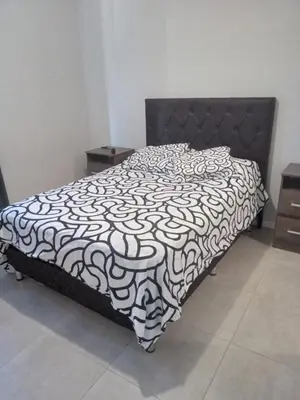 a bed with a black and white comforter in a bedroom at Departamento zipoli in Cordoba