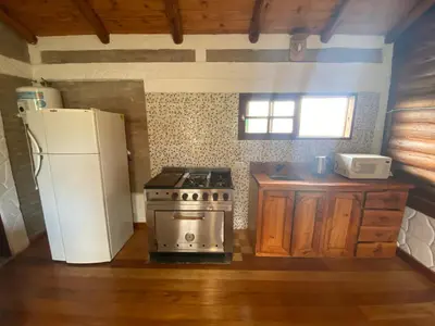 a kitchen with a stove and a refrigerator at Cabañas Las Serranitas 3 in Villa Parque Siquiman
