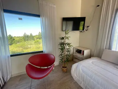 a bedroom with a red chair in front of a window at Verdena in Villa Amancay