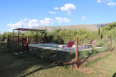 a pool with two chairs and a gazebo at Arawi Cabaña in Merlo