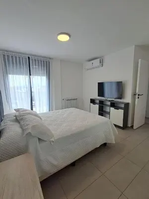 a white bedroom with a bed and a television at Av Velez Sarsfield 700 B Nueva Cordoba in Cordoba