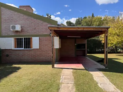 a brick house with an open garage in the yard at Casa Terra in Mina Clavero