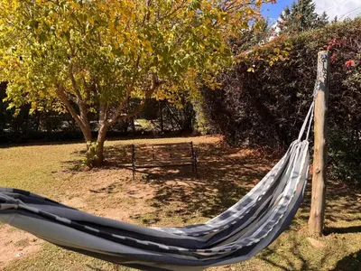 a hammock in a park with a bench at Casa Terra in Mina Clavero