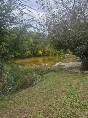 a river with brown water and some trees and grass at Cabañas Kay Pacha in San Antonio de Arredondo