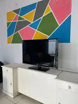 a tv on a white cabinet in front of a painting at Depto 3 in Río Cuarto