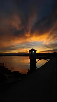 a lighthouse in the water with a sunset in the background at Departamentos La Morita in Embalse
